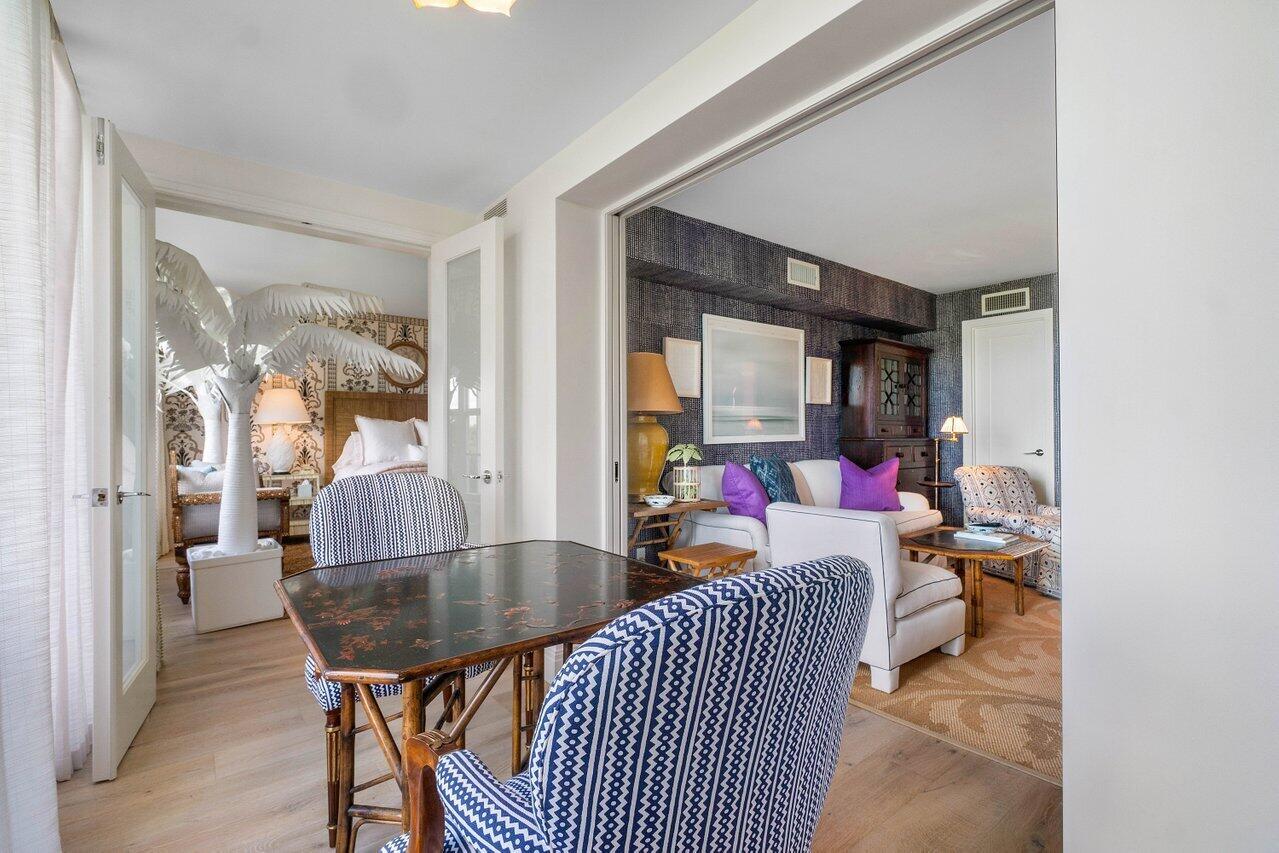 A dining area with patterned chairs leads into a living room with dark wallpaper — 2170 Ibis Isle Road # 3, Palm Beach FL 33480, PALM BEACH, FL