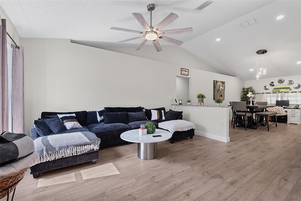 A living room with light wood flooring, a dark sectional sofa, and an arched mirror — 24 SEDGWICK TRAIL, PALM COAST, FL