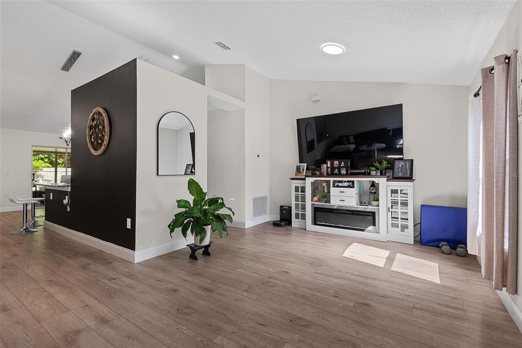 A living room features a large dark sectional sofa, a marble coffee table, and wood-look flooring — 24 SEDGWICK TRAIL, PALM COAST, FL