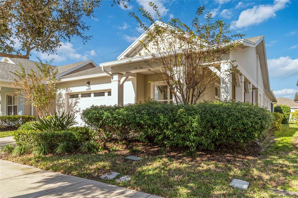 A single-story house with a white garage, covered porch, and large front hedge — 4909 W FOUNTAINWOOD DRIVE, ST CLOUD, FL
