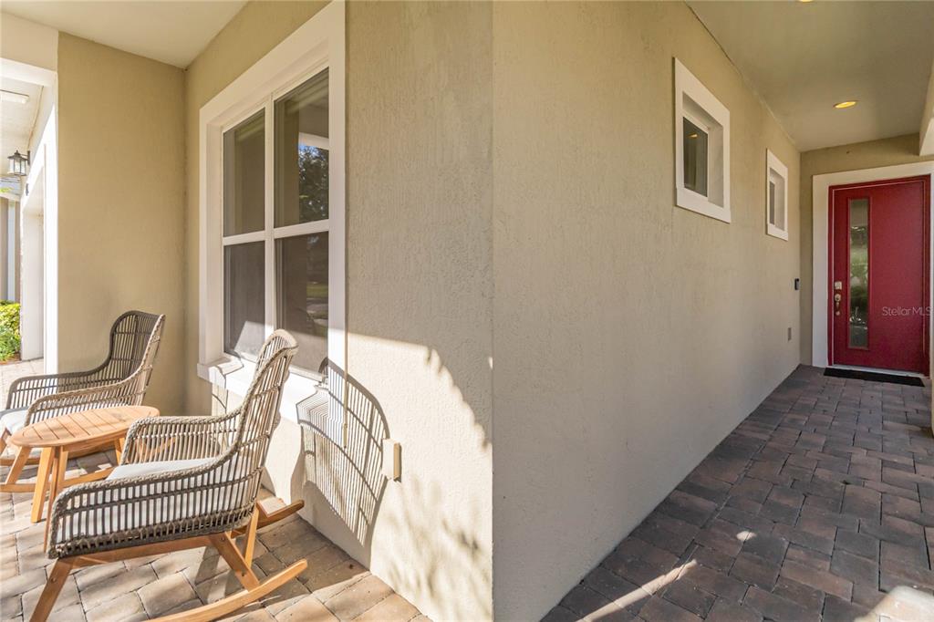 A covered porch features a red front door, a window, and two wicker rocking chairs — 4909 W FOUNTAINWOOD DRIVE, ST CLOUD, FL