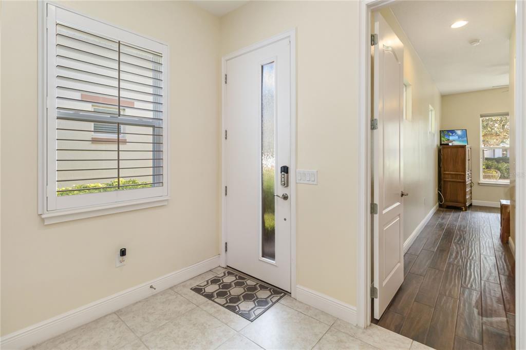 An entryway features a white front door, a window with shutters, and tile flooring — 4909 W FOUNTAINWOOD DRIVE, ST CLOUD, FL