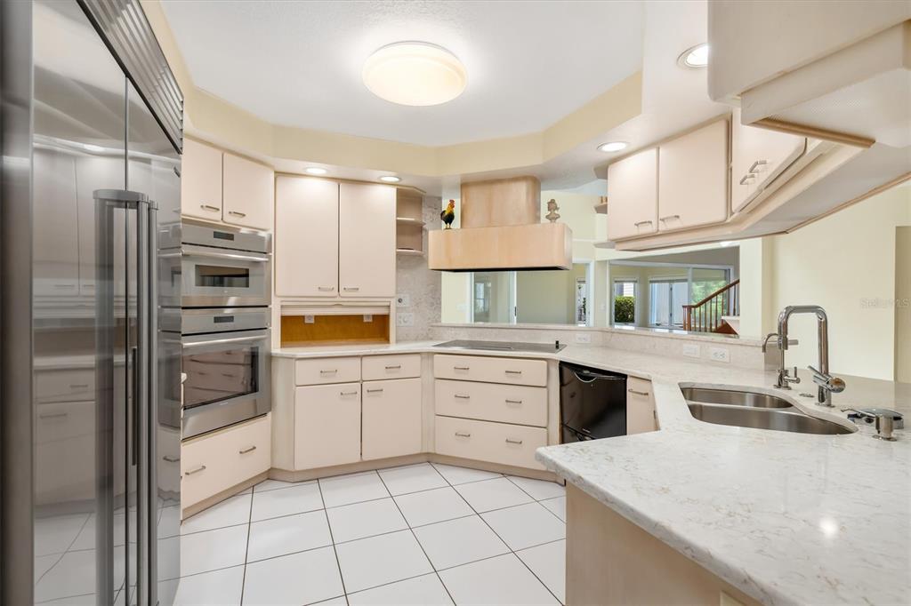 A kitchen features light-colored cabinets, stainless steel appliances, white countertops, and white tile flooring — 4405 HARBOR BOULEVARD, PORT CHARLOTTE, FL