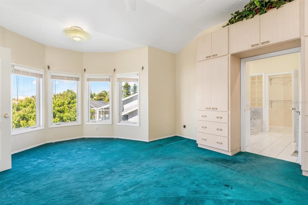 A bedroom with teal carpeting, a bay window, and built-in light-colored cabinetry — 4405 HARBOR BOULEVARD, PORT CHARLOTTE, FL