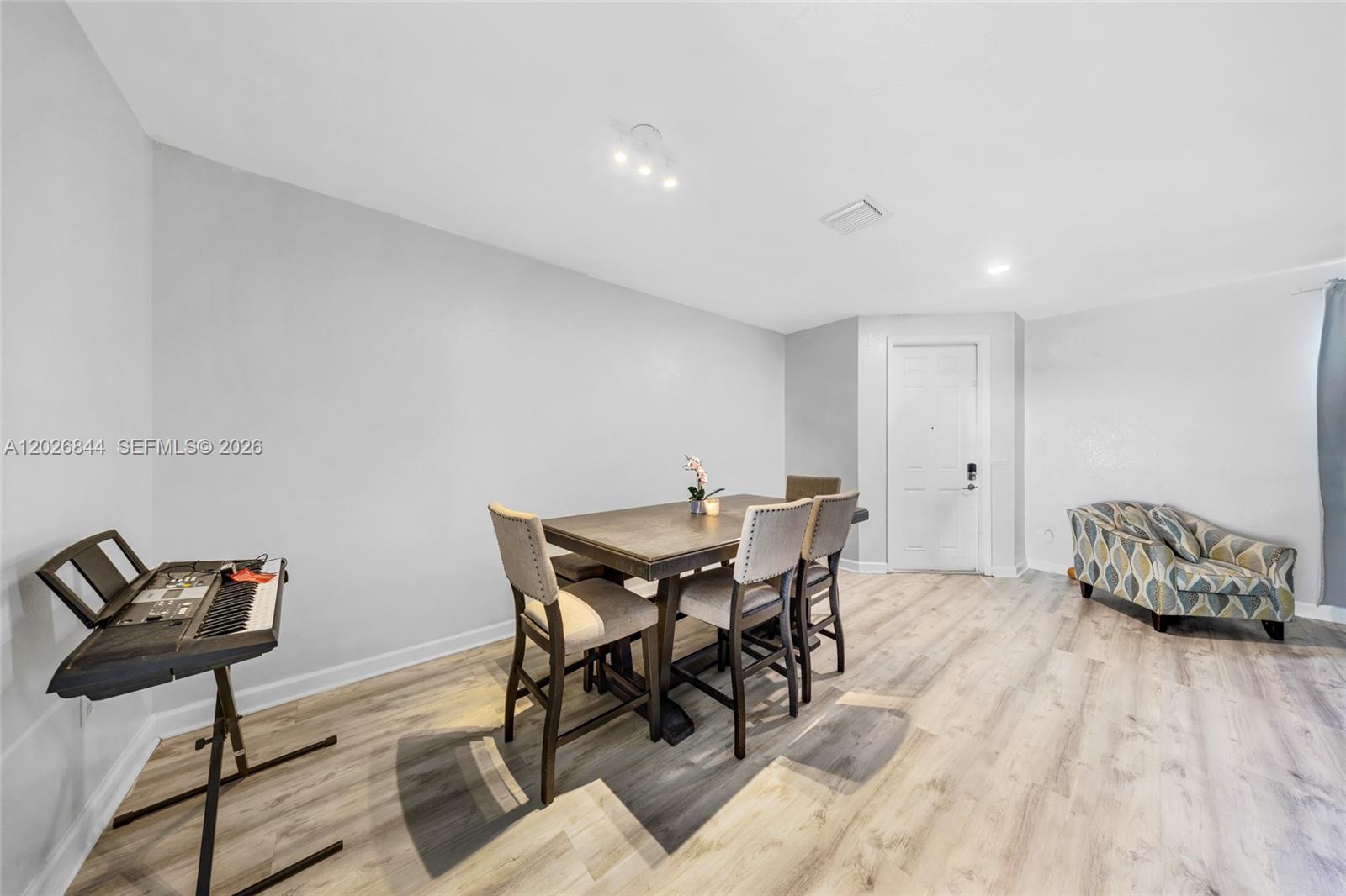 A dining area features a wooden table, four chairs, a keyboard stand, and light flooring — 9381 W 33rd Ln, Hialeah FL 33018, HIALEAH, FL