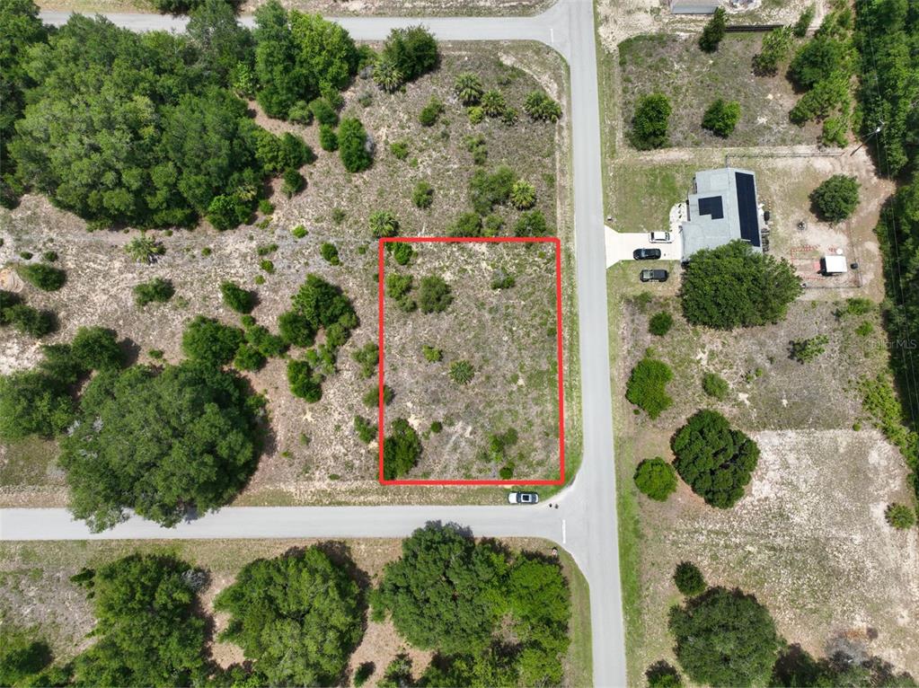An aerial view shows a vacant, rectangular lot outlined in red on a corner street — SW 82ND PL, DUNNELLON, FL