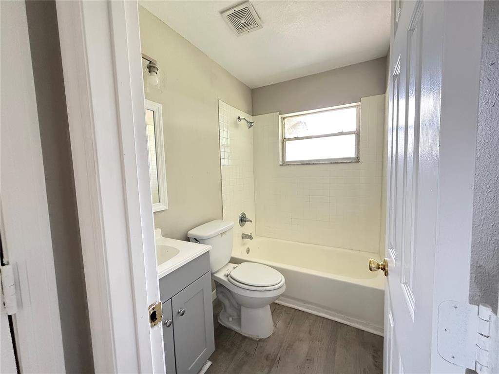 A bathroom features a gray vanity, a white toilet, and a tub-shower combination — 116 COURT STREET SW, FORT MEADE, FL