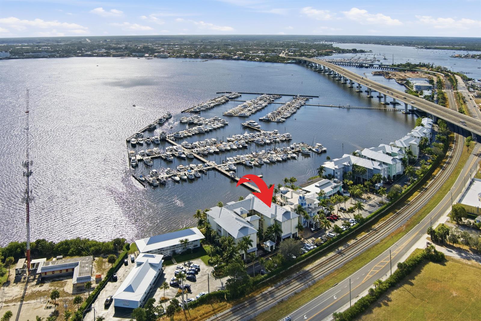 An aerial view shows a waterfront condominium complex with a marina and a nearby bridge — 975 NW Flagler Avenue # 307, Stuart FL 34994, STUART, FL