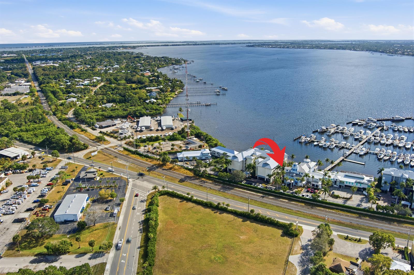 An aerial view shows a waterfront residential complex with a marina and nearby railroad tracks — 975 NW Flagler Avenue # 307, Stuart FL 34994, STUART, FL