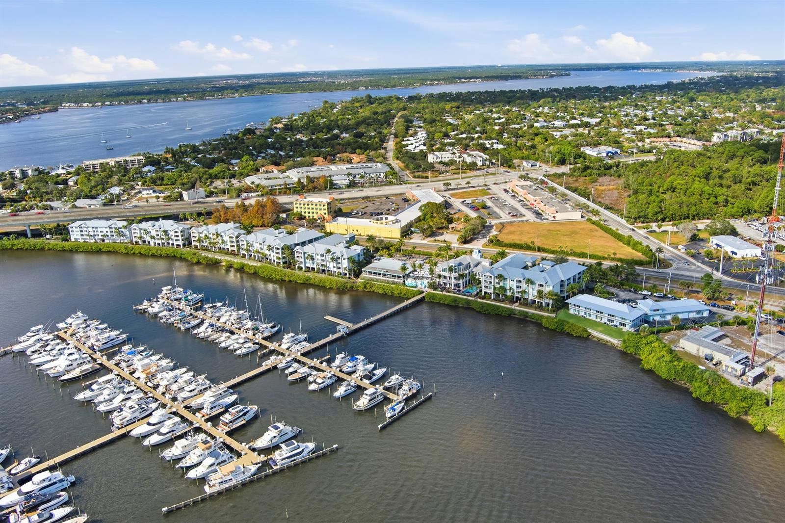 An aerial view shows a marina with numerous docked boats beside a waterfront apartment complex — 975 NW Flagler Avenue # 307, Stuart FL 34994, STUART, FL