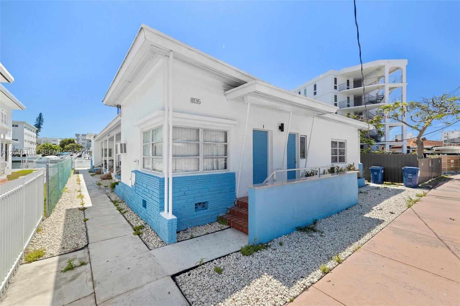 A white and blue single-story building with two blue doors sits beside a sidewalk — 8135 Crespi Blvd # 4, Miami Beach FL 33141, MIAMI BEACH, FL