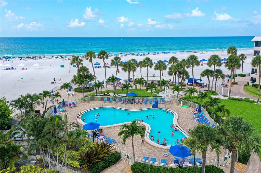 An aerial view of a swimming pool surrounded by palm trees next to a sandy beach — 5920 MIDNIGHT PASS ROAD UNIT 406, SARASOTA, FL