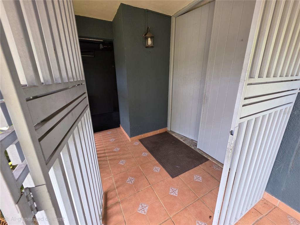 An outdoor entryway features a tiled floor, a dark mat, and a white gate — 37 RIO TURABO UNIT AW11, BAYAMON, PR