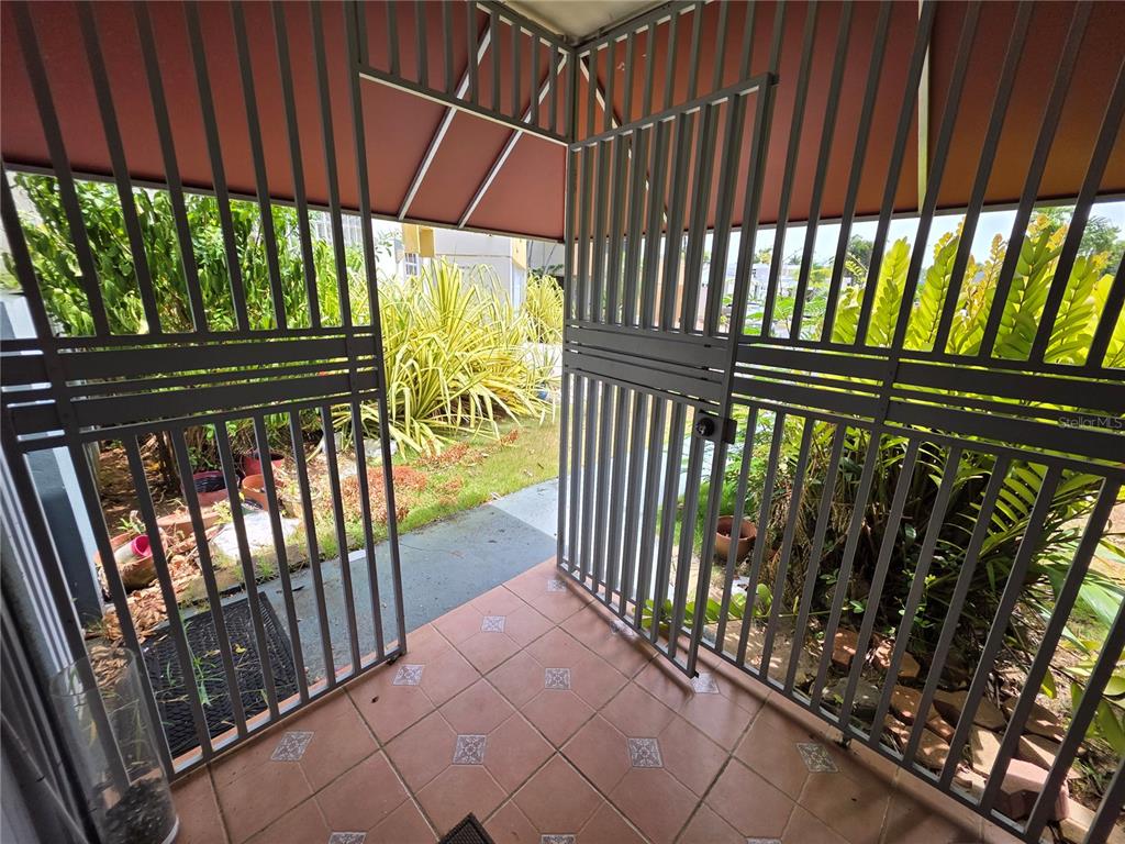 A tiled patio area is enclosed by metal security gates and a reddish awning — 37 RIO TURABO UNIT AW11, BAYAMON, PR