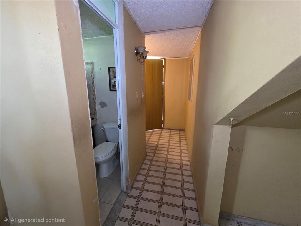 A hallway with tiled flooring leads to a bathroom and an exterior door — 37 RIO TURABO UNIT AW11, BAYAMON, PR
