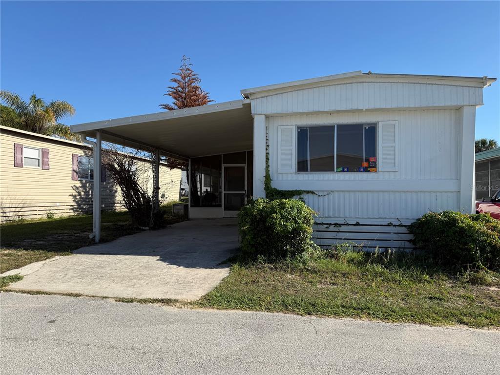 A white mobile home features a carport, a screened-in porch, and a concrete driveway — 17730 US HWY 27 UNIT 43, CLERMONT, FL
