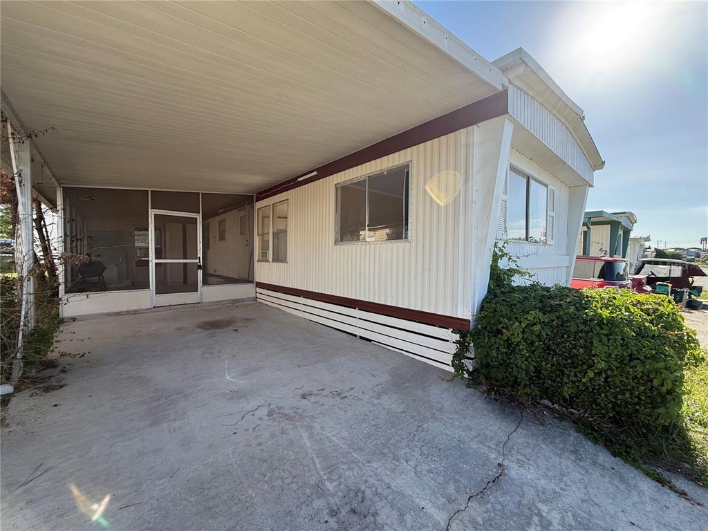 A mobile home exterior features a concrete carport, a screened-in porch, and white siding — 17730 US HWY 27 UNIT 43, CLERMONT, FL