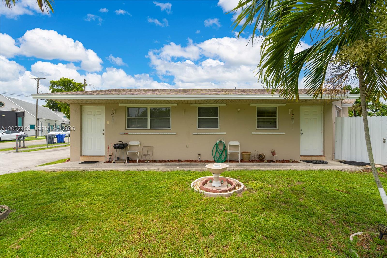 The exterior of a single-story duplex features a grassy yard, a fountain, and two doors — 5829 Taylor St, Hollywood FL 33021, HOLLYWOOD, FL