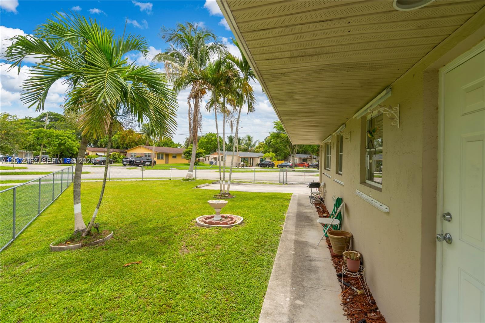A view of a grassy yard with palm trees and a concrete walkway — 5829 Taylor St, Hollywood FL 33021, HOLLYWOOD, FL
