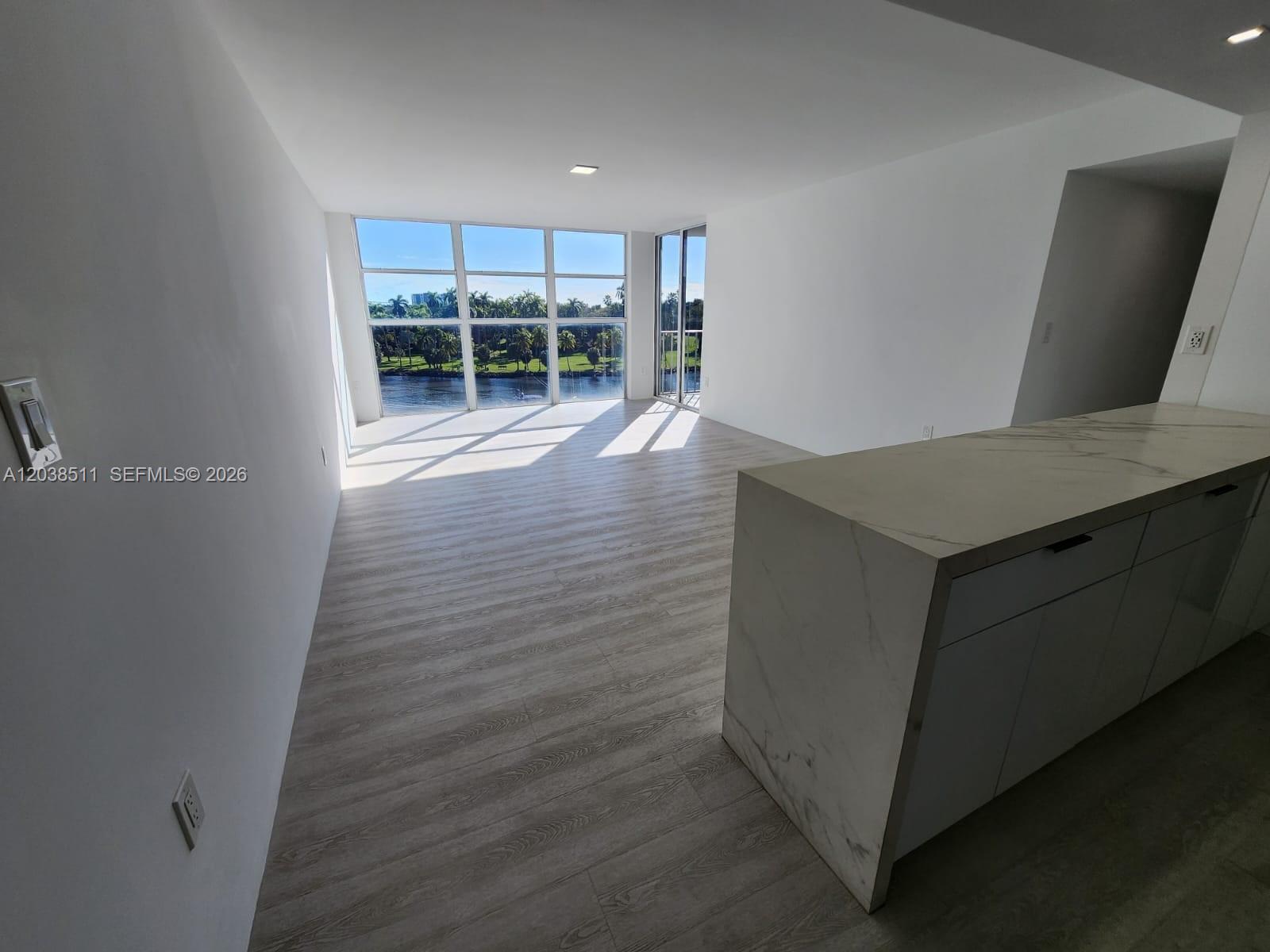 An open-concept living area features light wood-look flooring, a marble-topped island, and floor-to-ceiling windows — 1700 NW N River Dr # 606, Miami FL 33125, MIAMI, FL