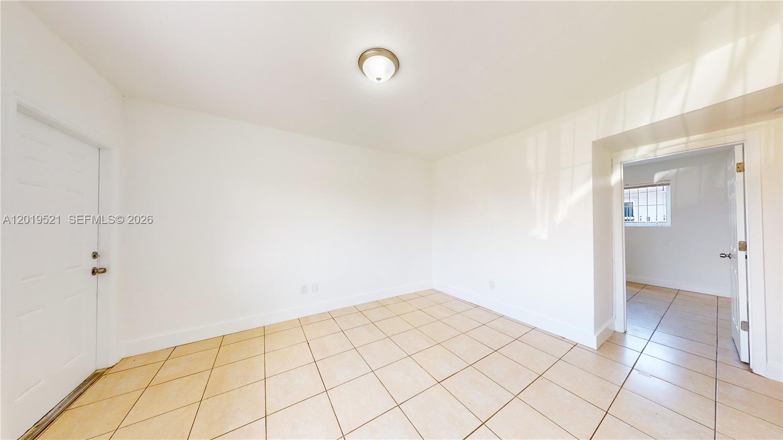 An empty room features white walls, beige tile flooring, and a ceiling light fixture — 1190 NW 65th St # 2, Miami FL 33150, MIAMI, FL