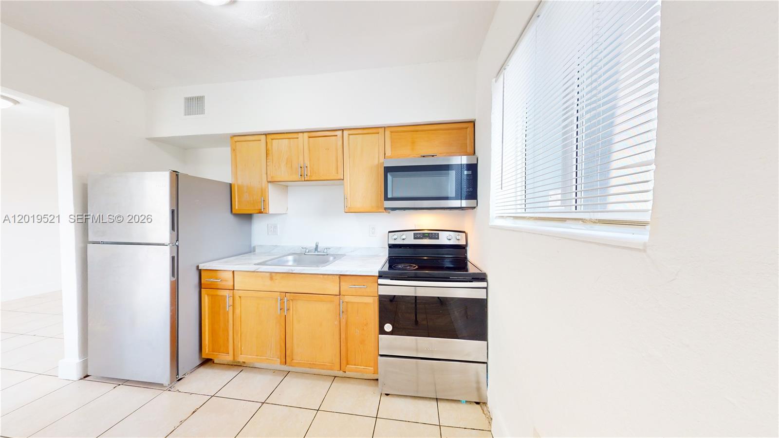 A kitchen features light wood cabinets, stainless steel appliances, and tile flooring — 1190 NW 65th St # 2, Miami FL 33150, MIAMI, FL