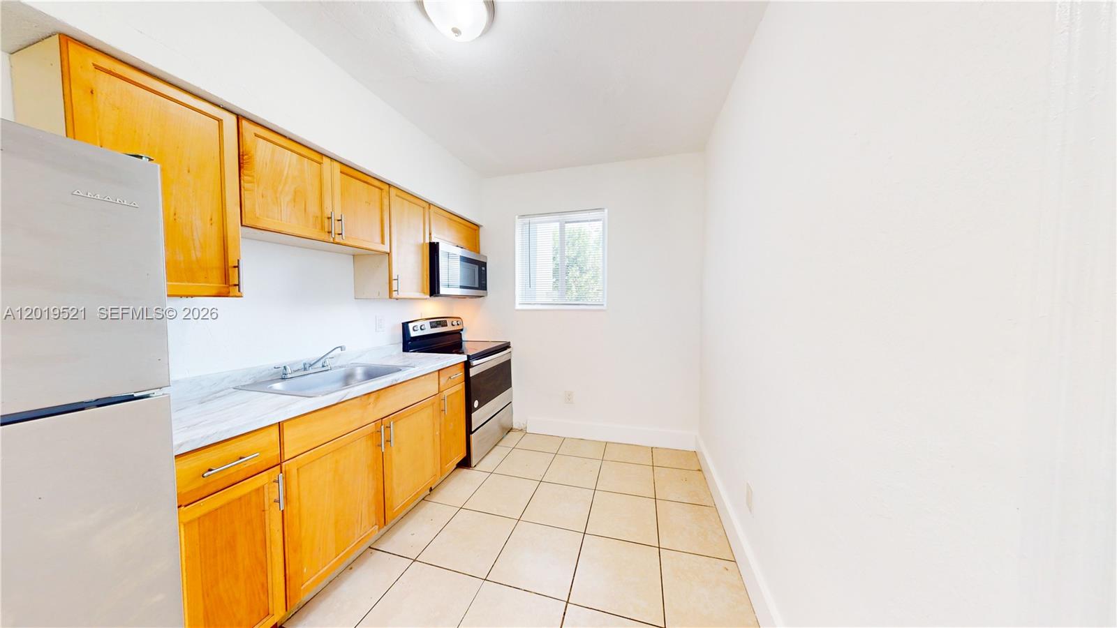 A kitchen features light wood cabinets, a stainless steel refrigerator, and beige floor tiles — 1190 NW 65th St # 2, Miami FL 33150, MIAMI, FL