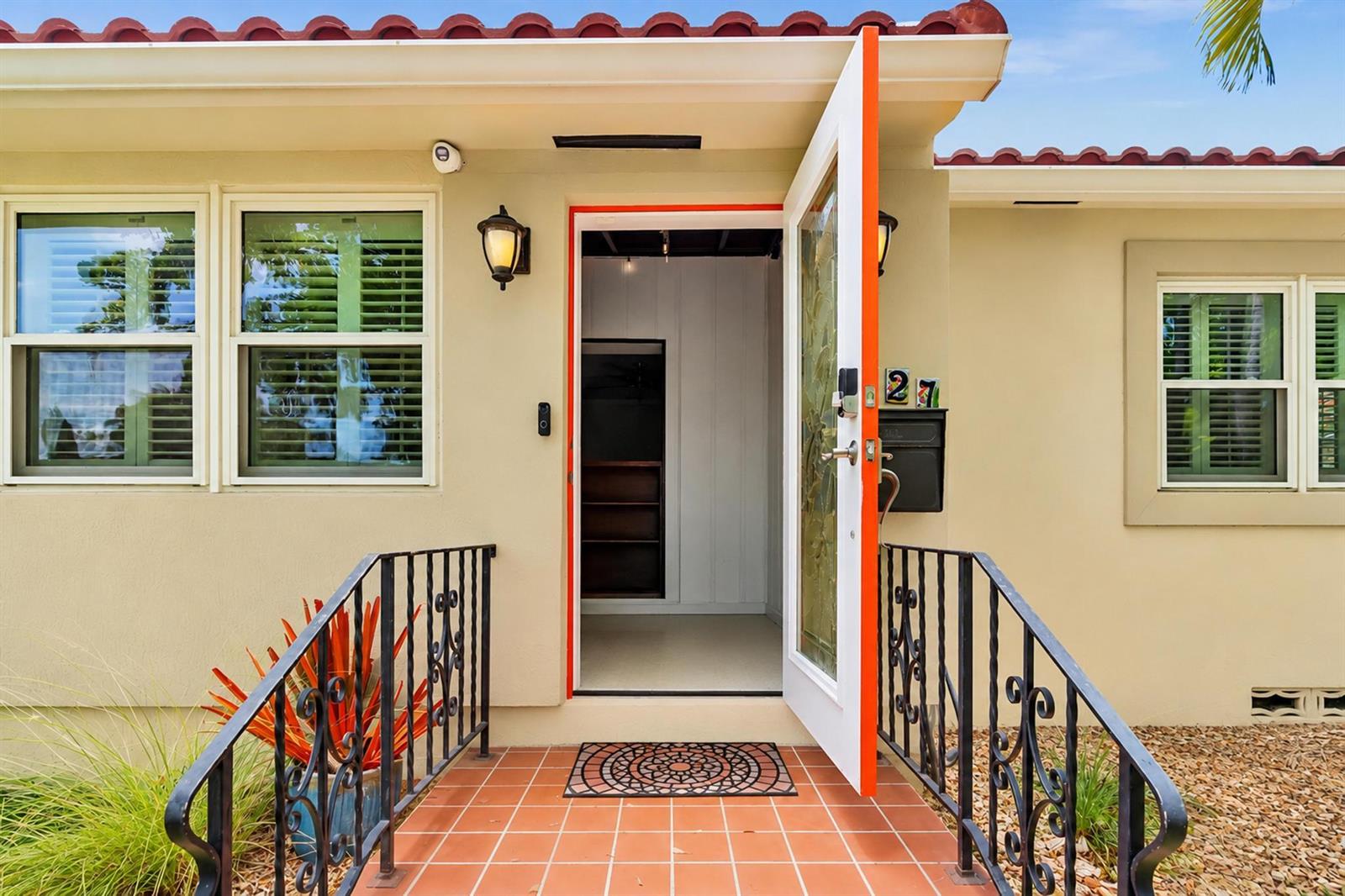 The exterior of a house features a tiled porch, black metal railings, and an open door — 1527 Mayo Street, Hollywood FL 33020, HOLLYWOOD, FL