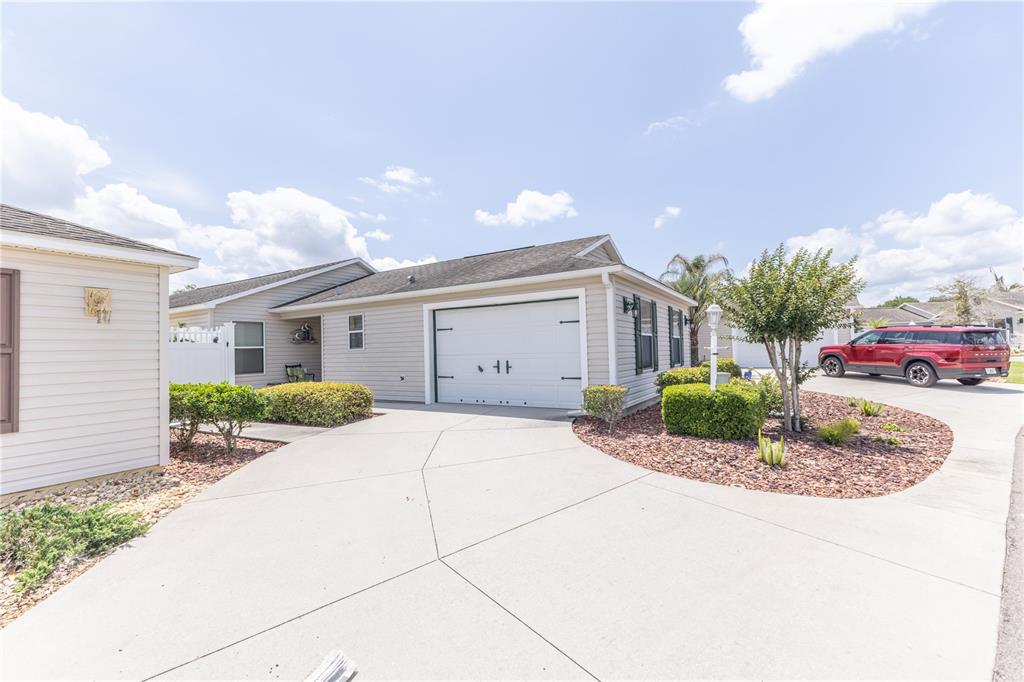A beige single-story house features a white garage door and a concrete driveway — 2306 NACKMAN PLACE, THE VILLAGES, FL