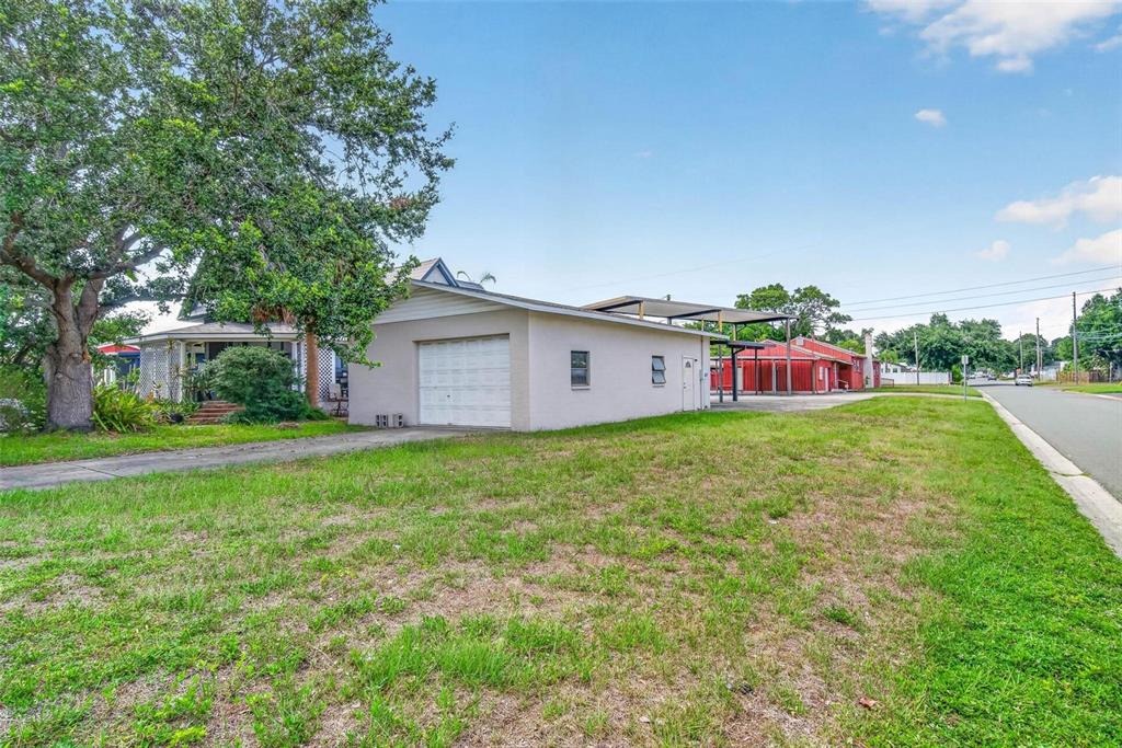 A detached garage with a white door sits on a grassy lot near a house — 2600 25TH AVENUE N, ST PETERSBURG, FL