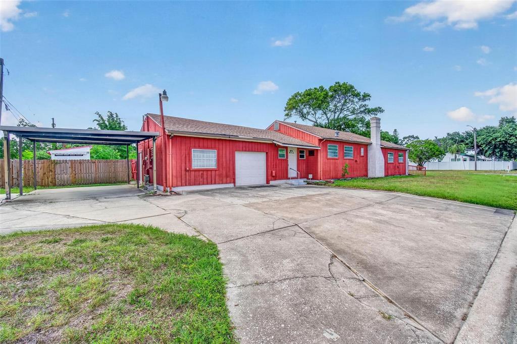 A red, single-story house with a white garage door, attached carport, and concrete driveway — 2600 25TH AVENUE N, ST PETERSBURG, FL