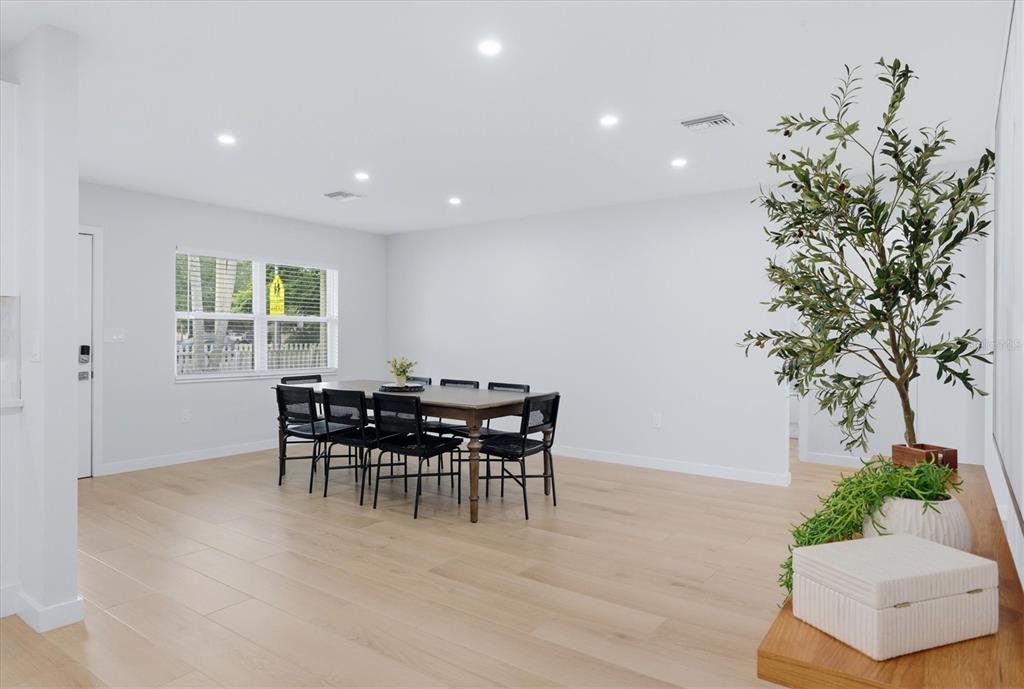 A dining room features light wood flooring, a dark table with chairs, and recessed lighting — 4411 BENEVA ROAD, SARASOTA, FL
