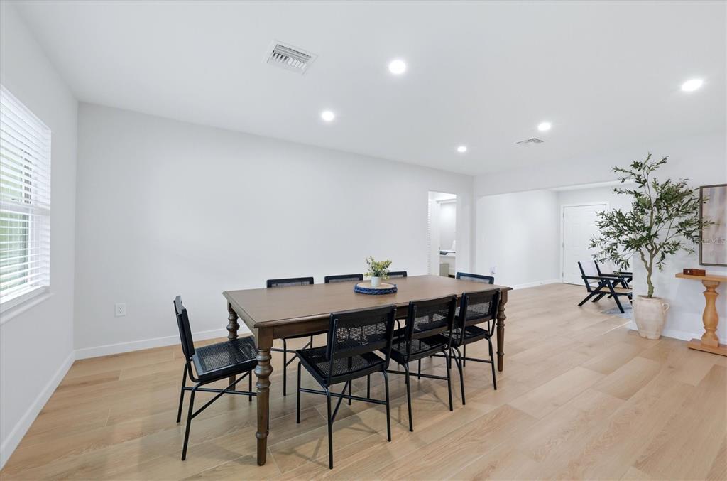 A dining room with a wooden table, black chairs, light wood flooring, and recessed lighting — 4411 BENEVA ROAD, SARASOTA, FL