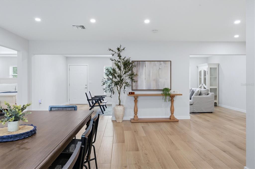 A dining area with wood floors and a console table leads to an adjacent living space — 4411 BENEVA ROAD, SARASOTA, FL