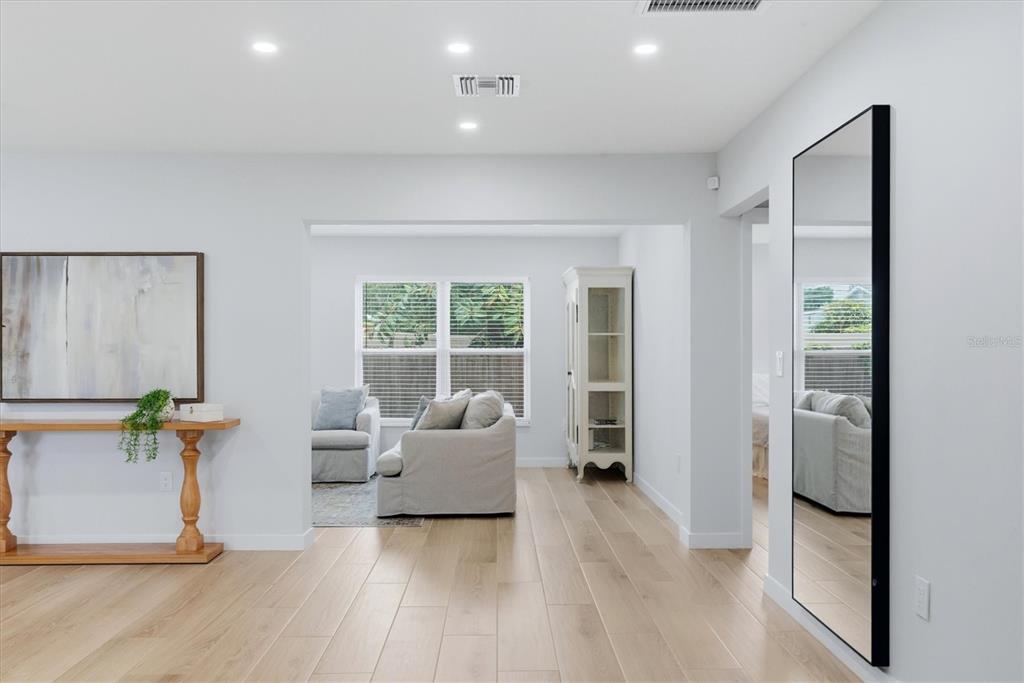 A bright living area features light wood flooring, a large wall mirror, and a console table — 4411 BENEVA ROAD, SARASOTA, FL