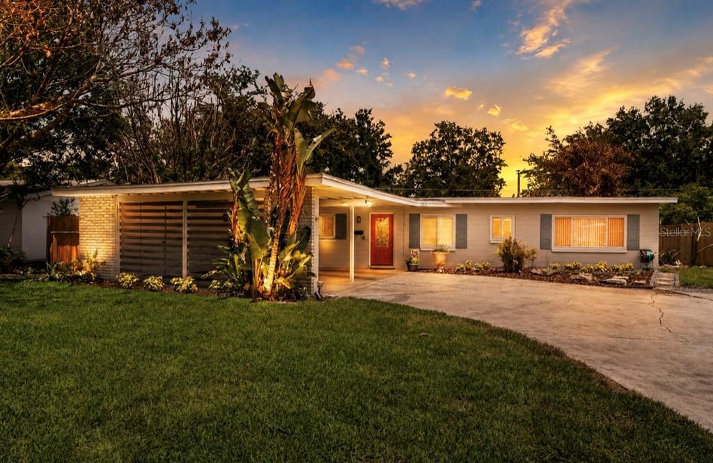 A single-story mid-century modern house with a red front door and a concrete driveway — 2215 WOODCREST DRIVE, WINTER PARK, FL