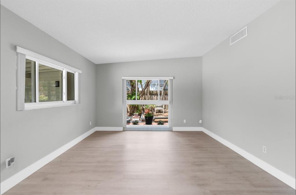 An empty room with light gray walls, wood-look flooring, two windows, and a sliding door — 2215 WOODCREST DRIVE, WINTER PARK, FL