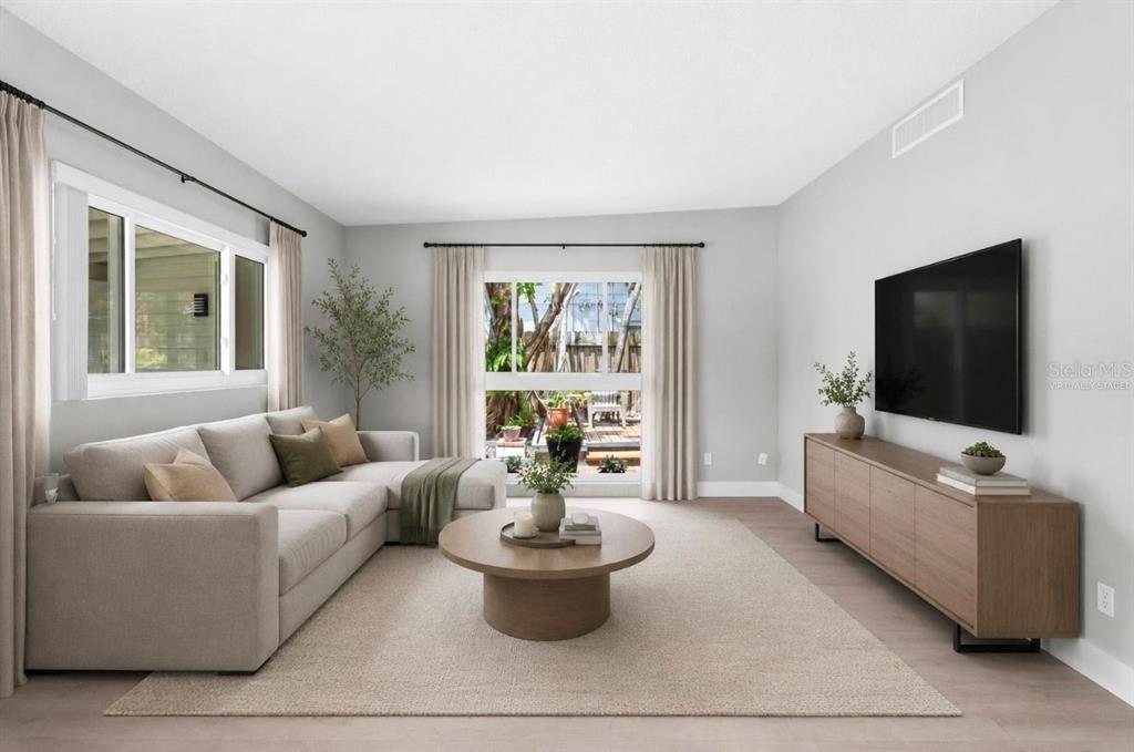 A living room with a sectional sofa, round coffee table, media console, and large windows — 2215 WOODCREST DRIVE, WINTER PARK, FL