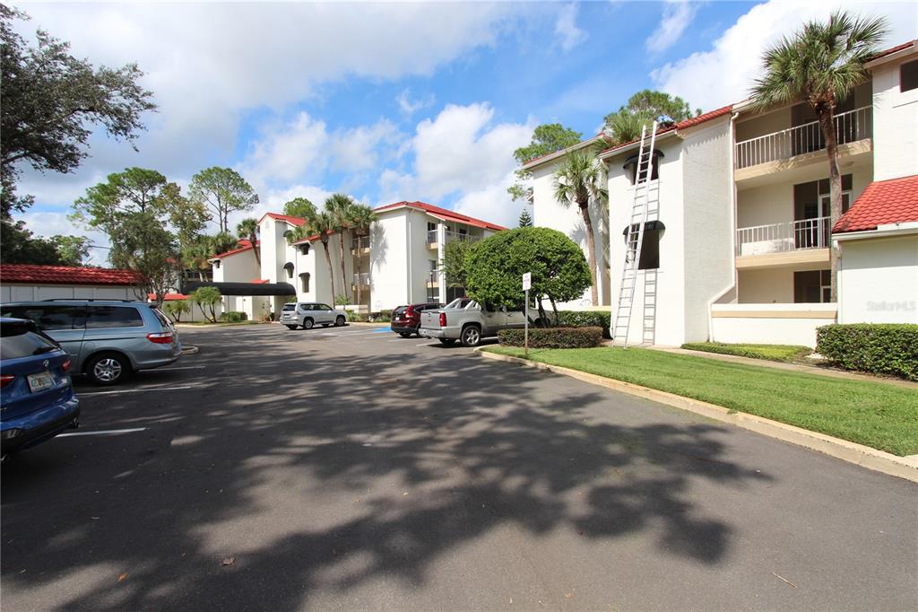 A parking lot sits in front of multi-story residential apartment buildings with red tile roofs — 451 HAMPTONCREST CIRCLE UNIT 307, LAKE MARY, FL