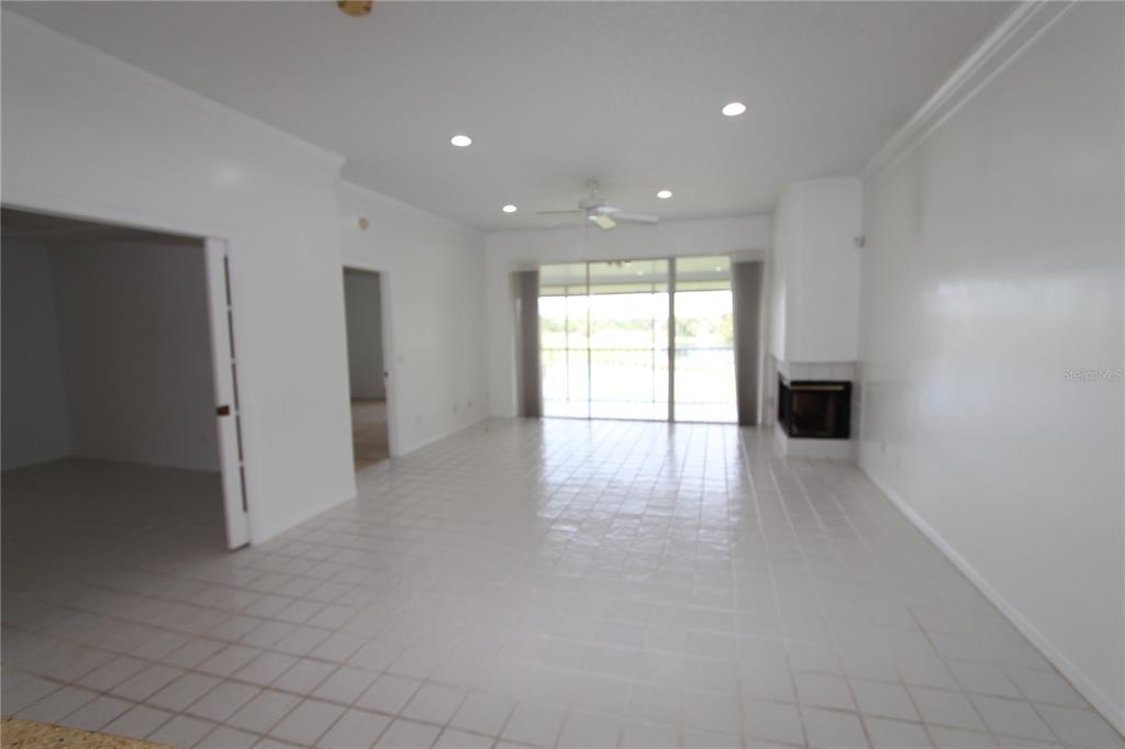 A bright living room features white tile floors, a fireplace, and sliding glass patio doors — 451 HAMPTONCREST CIRCLE UNIT 307, LAKE MARY, FL