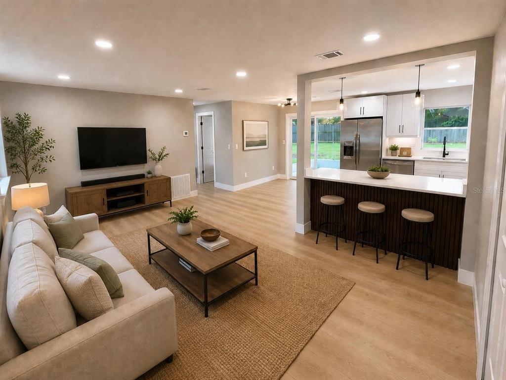 A living room with a sofa and television opens to a kitchen with a breakfast bar — 14565 SW 35TH TERRACE ROAD, OCALA, FL