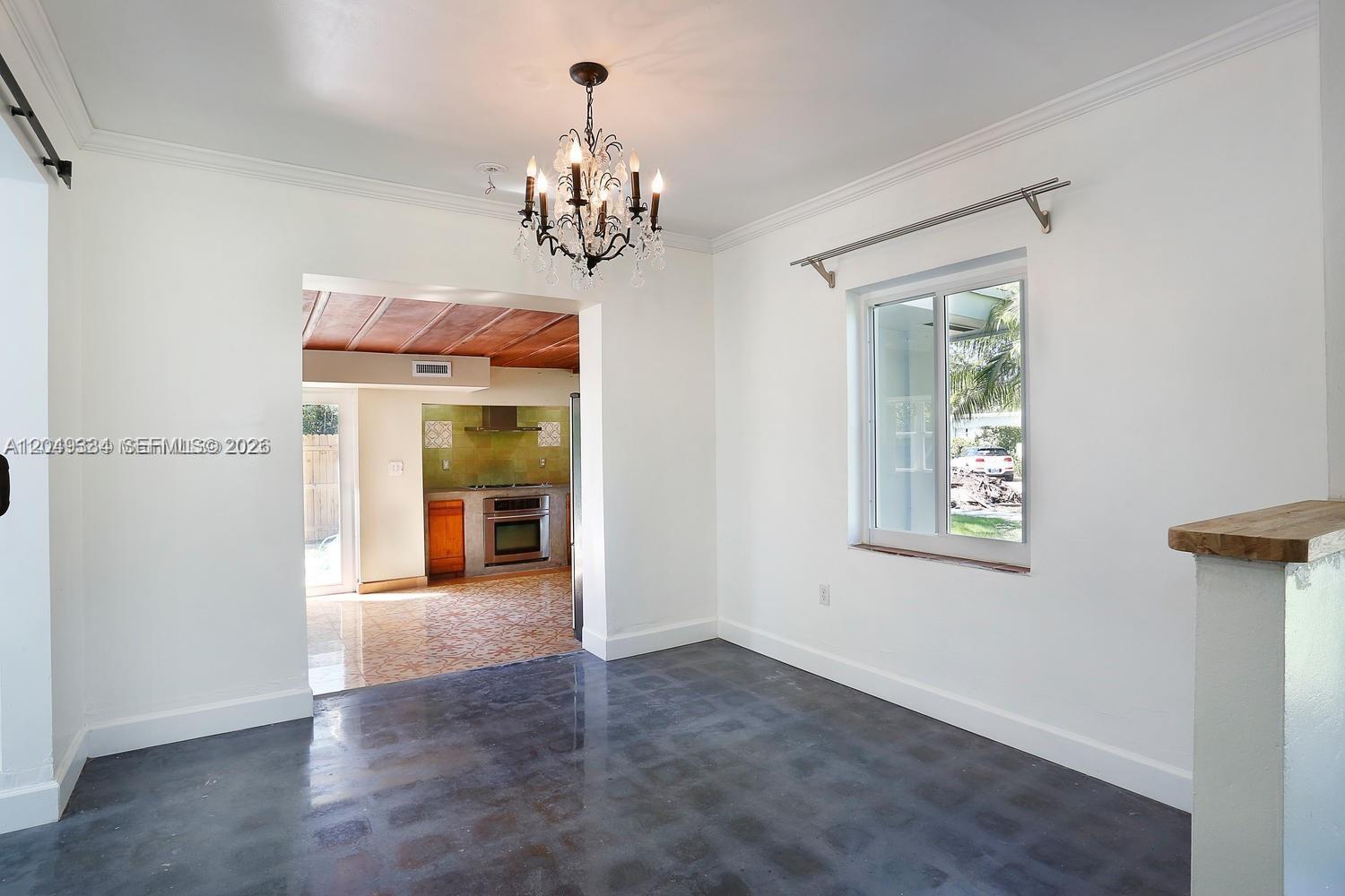A dining room with a chandelier, dark concrete floors, and a view into the kitchen — 6116 SW 46th Ter, Miami FL 33155, MIAMI, FL