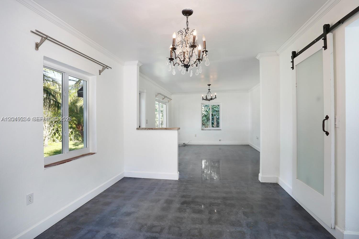 An interior view of a room with white walls, gray concrete floors, and two chandeliers — 6116 SW 46th Ter, Miami FL 33155, MIAMI, FL