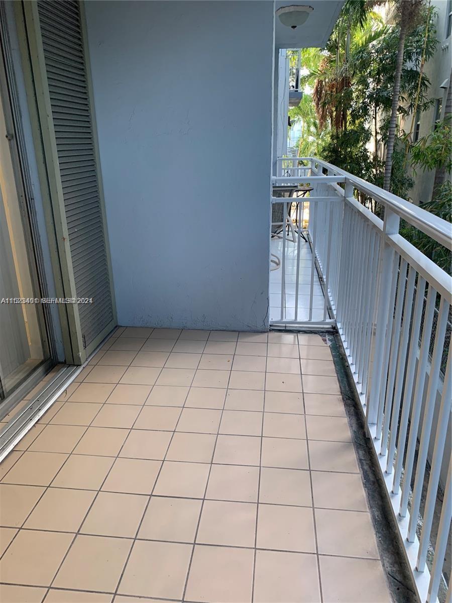 A tiled balcony features a white metal railing and a sliding glass door — 947 Lenox Ave # 204, Miami Beach FL 33139, MIAMI BEACH, FL