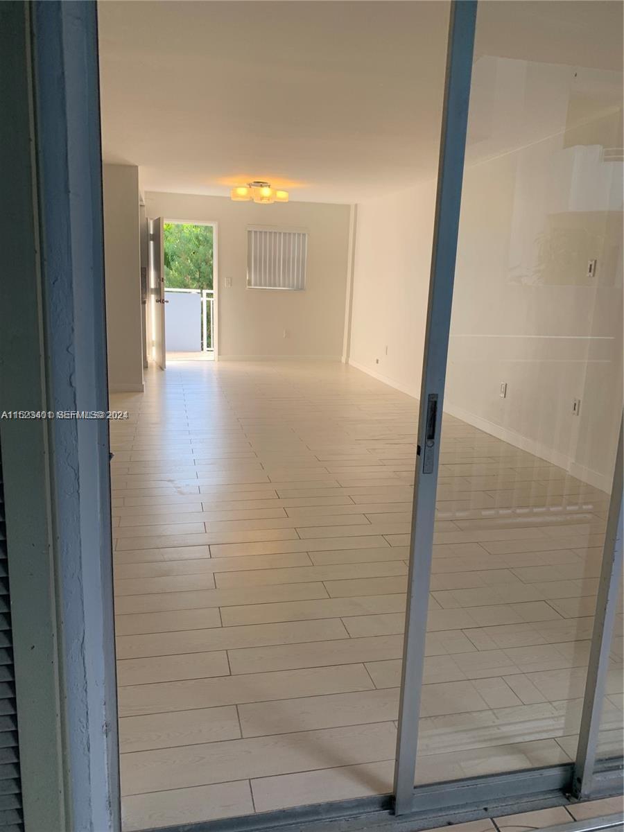 An interior view of a room with light-colored tile flooring and a sliding glass door — 947 Lenox Ave # 204, Miami Beach FL 33139, MIAMI BEACH, FL