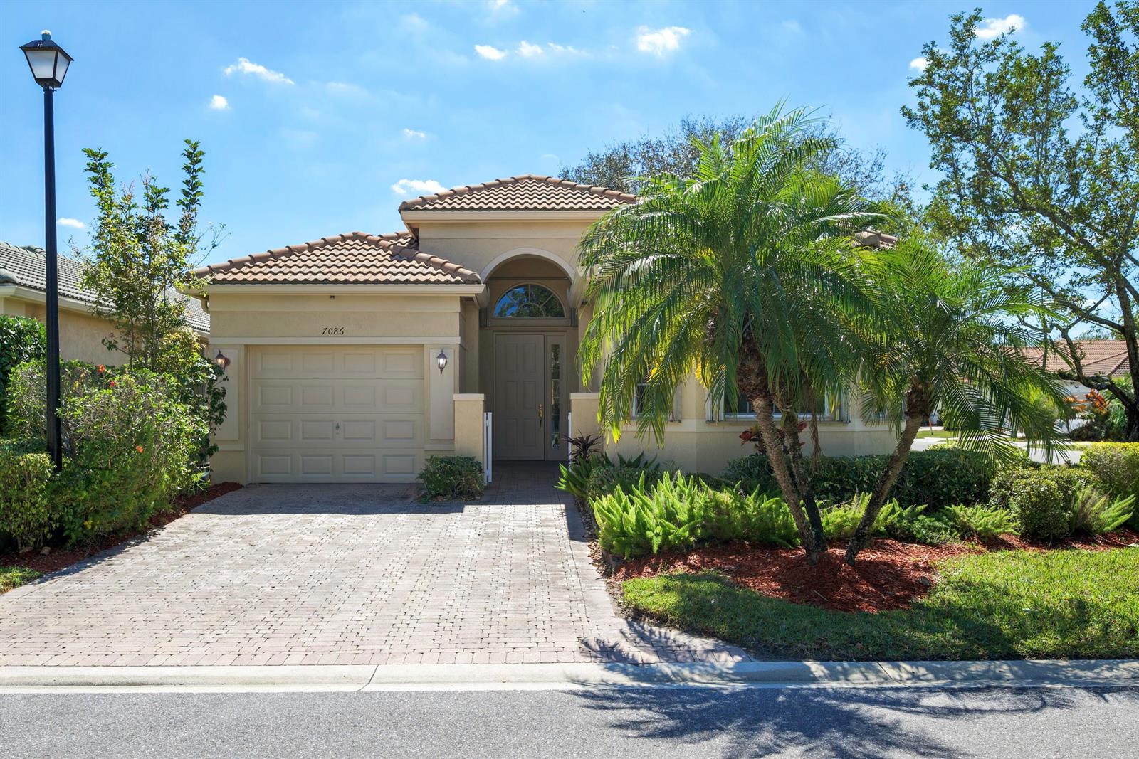 A single-story house with a tiled roof, a one-car garage, and a palm tree out front — 7086 Del Corso Lane, Delray Beach FL 33446, DELRAY BEACH, FL