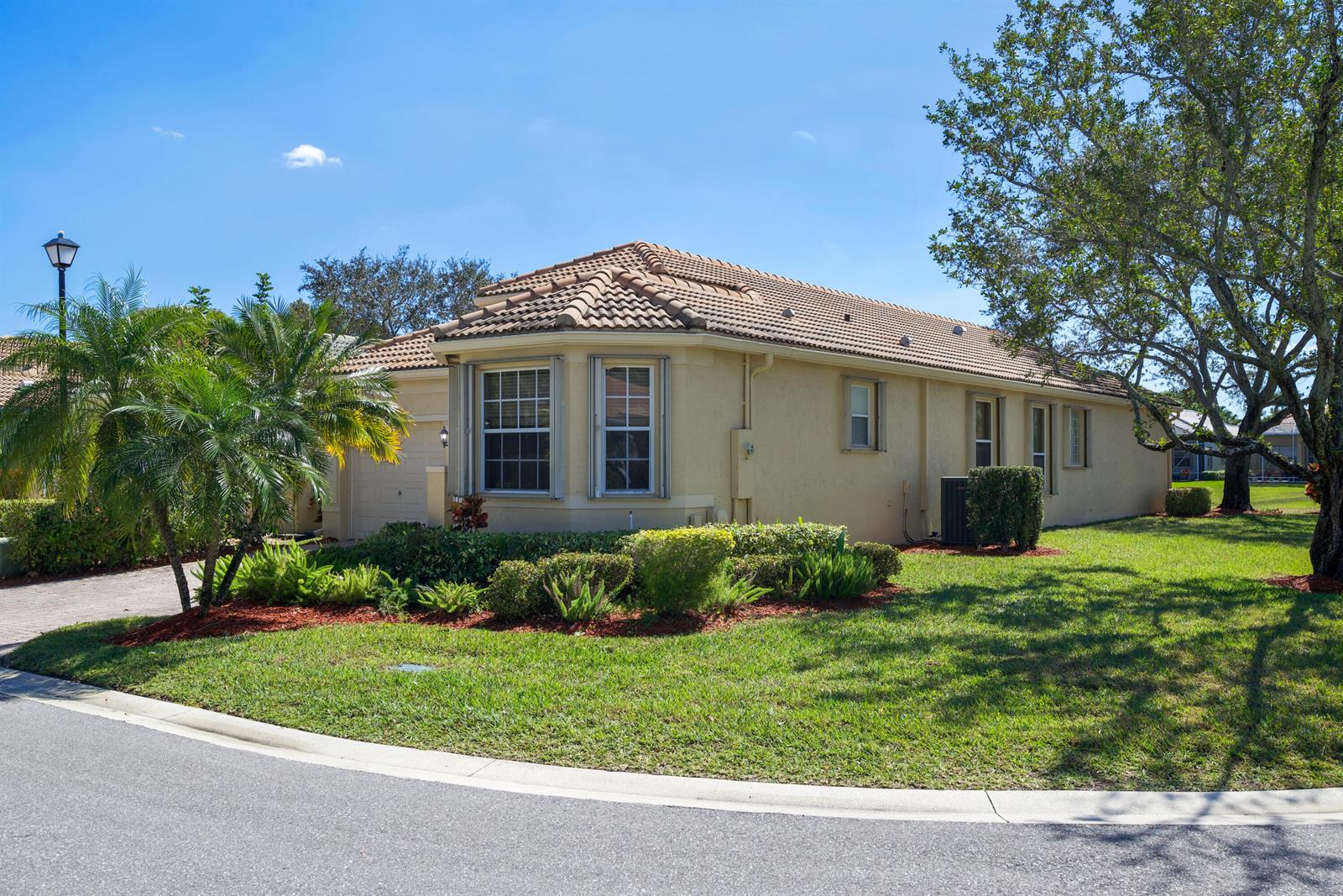 A single-story house with a tile roof and beige stucco exterior sits on a lawn — 7086 Del Corso Lane, Delray Beach FL 33446, DELRAY BEACH, FL
