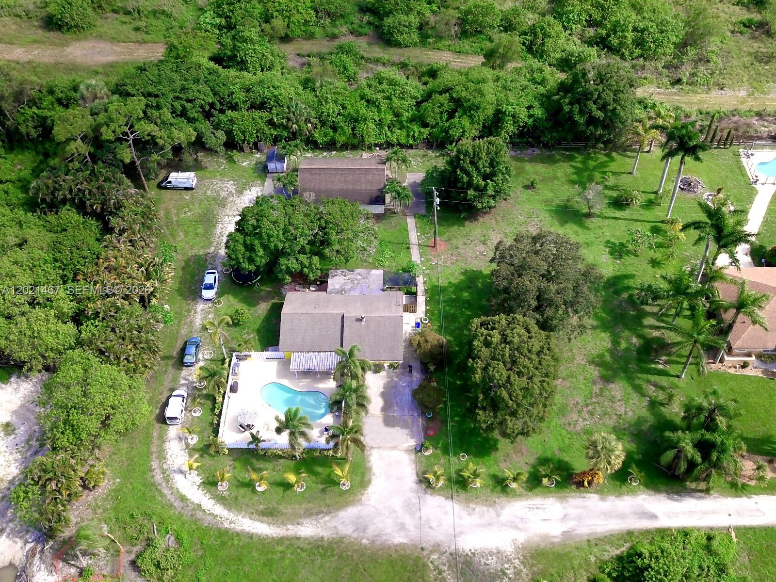 An aerial view shows a house with a pool, detached garage, and surrounding green space — 10646 Barn Rd, Lake Worth FL 33449, LAKE WORTH, FL