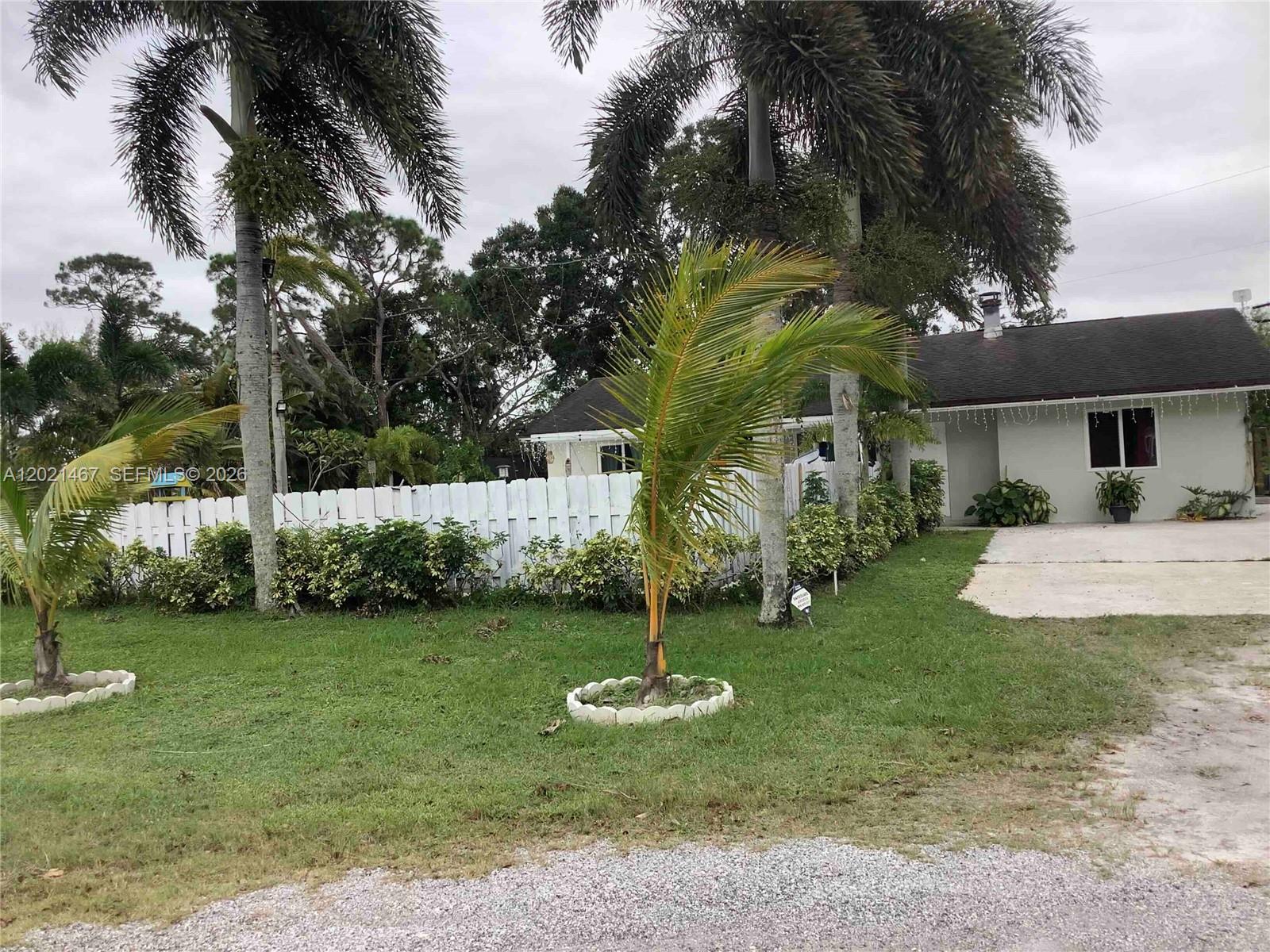 A single-story house with a white fence and palm trees in the front yard — 10646 Barn Rd, Lake Worth FL 33449, LAKE WORTH, FL