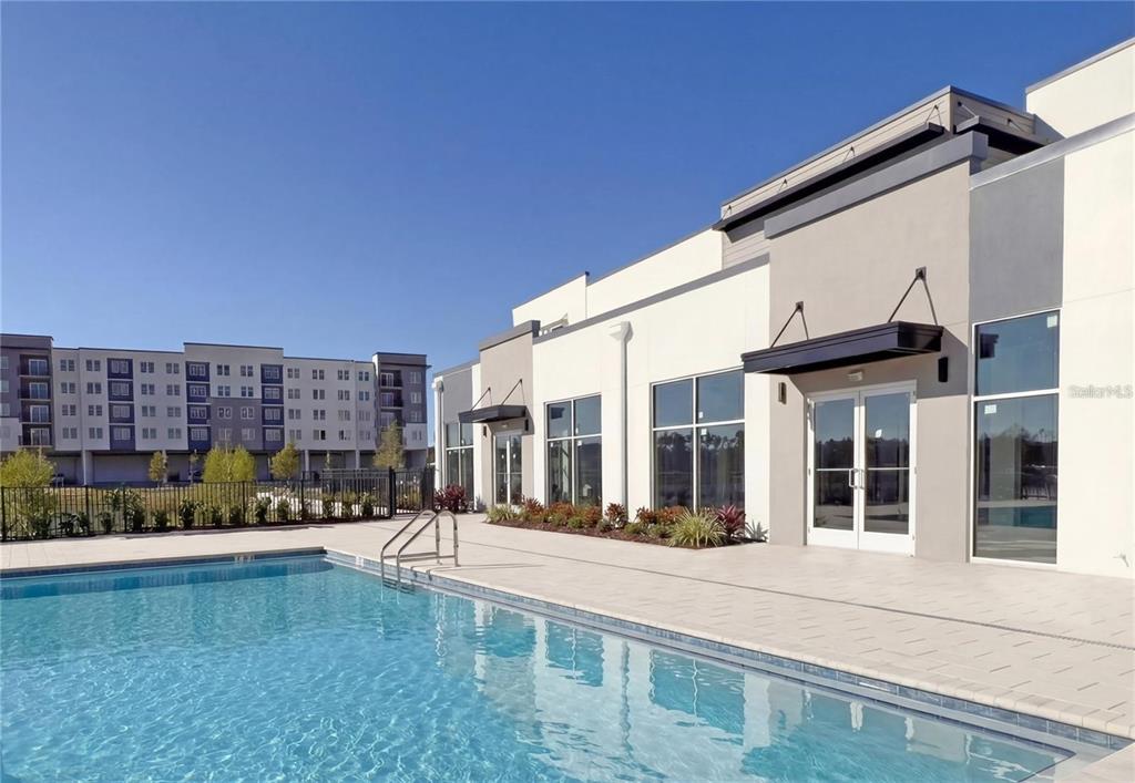 A swimming pool sits in front of a modern building with large glass windows — 5579 MILLENIA BOULEVARD UNIT 110, ORLANDO, FL